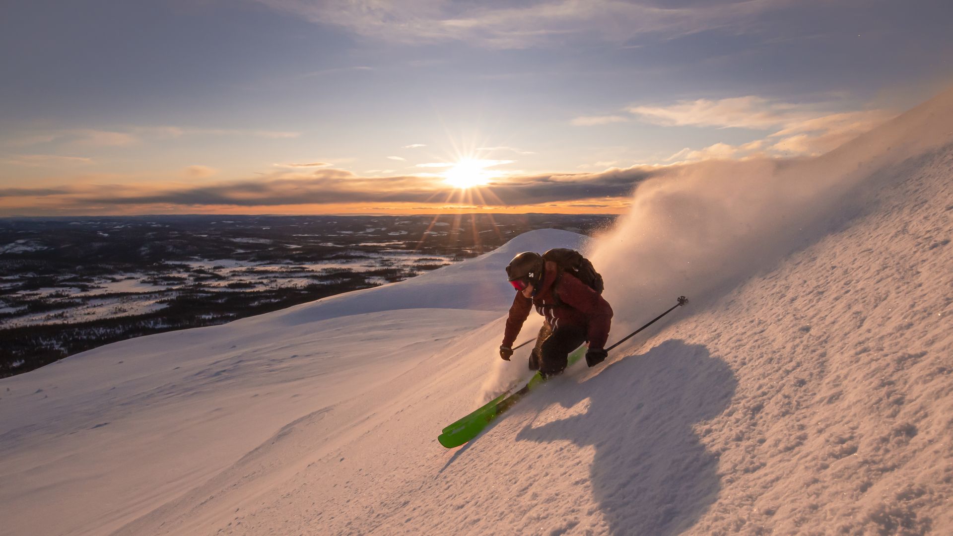 Skiër in actie op een besneeuwde berghelling bij zonsondergang.